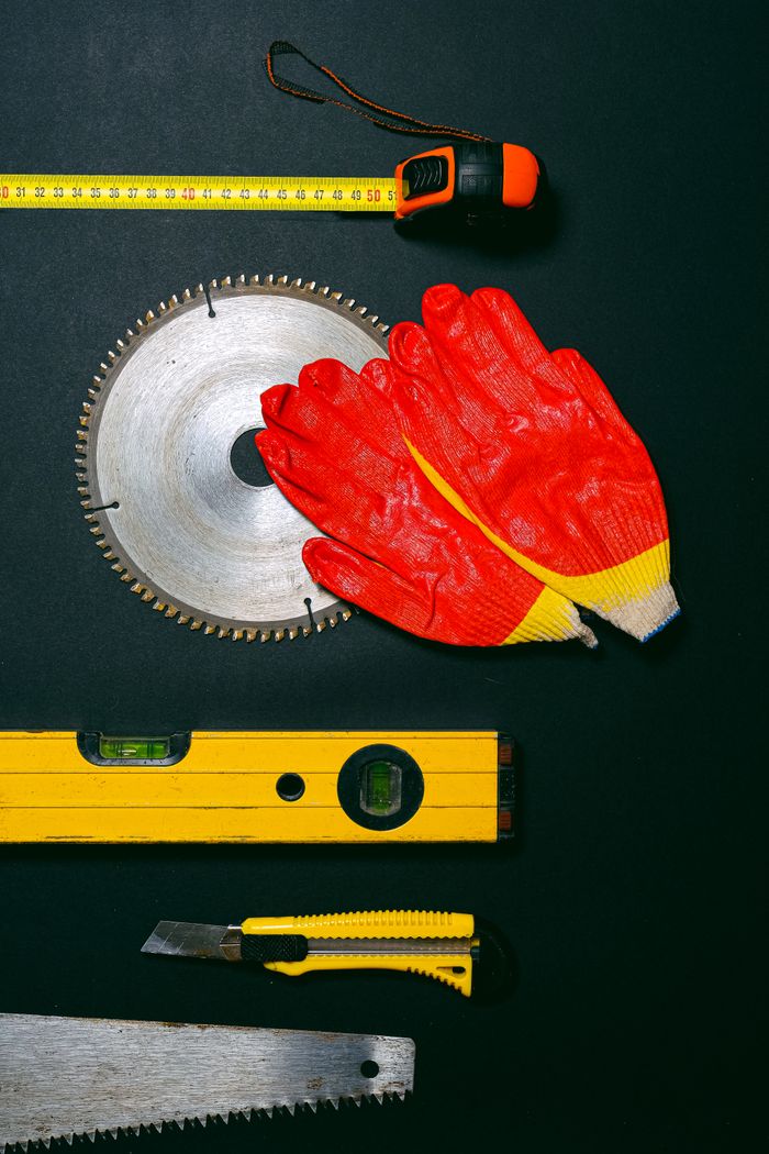 A collection of construction tools and safety gloves laid on a flat surface, ideal for construction themes.